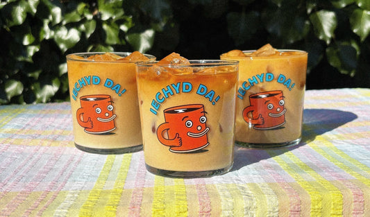 Our signature iechyd da glass filled with delicious iced coffee on an outside table on a warm sunny day